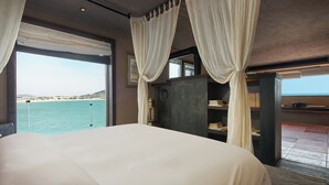 A bedroom with a large bed, a view of the sea, and a bookshelf. - Nordsee Manor by Arcadia Collection (Qingdao)