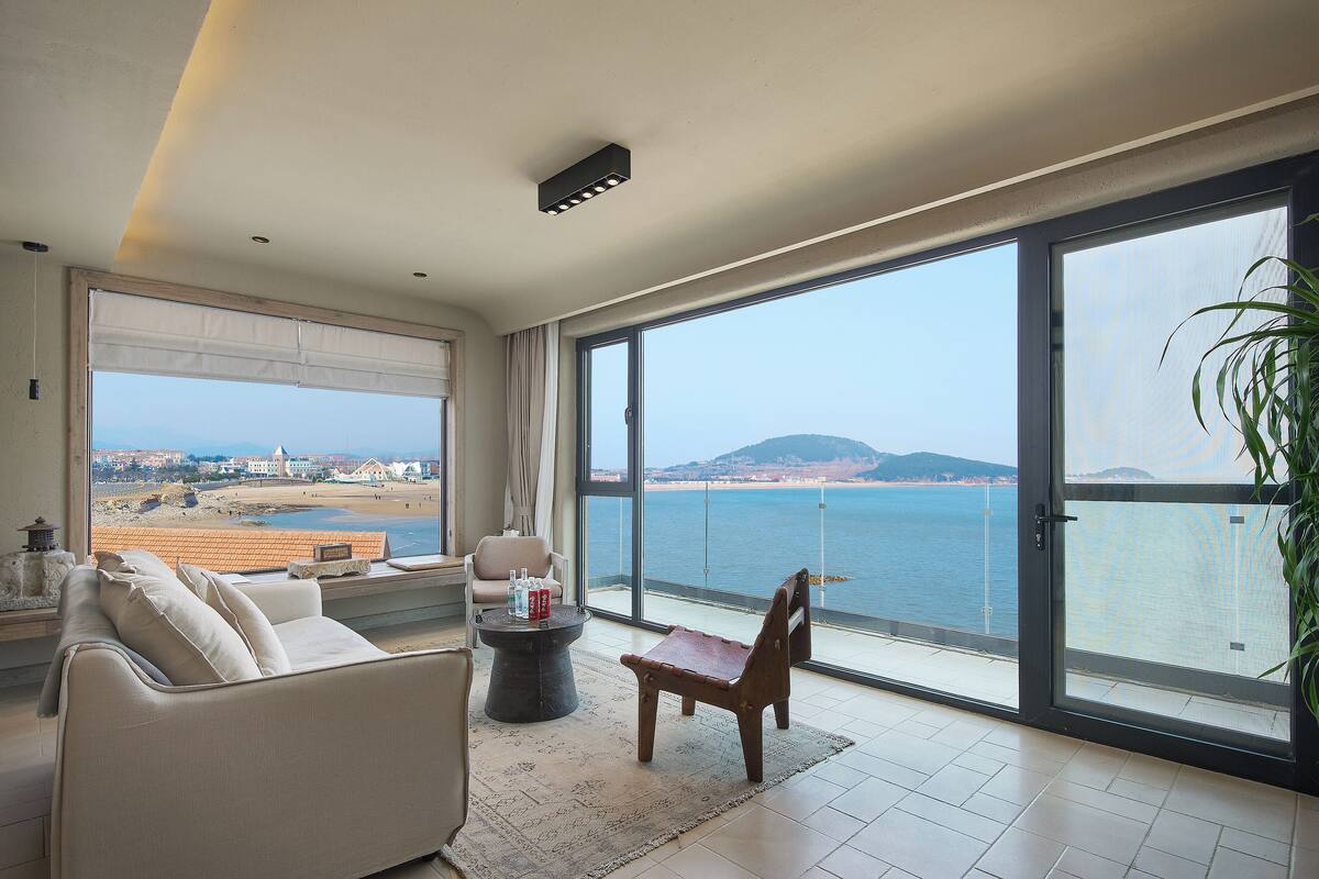 Amplia sala de estar con un ventanal que ofrece vistas al mar y a la playa.