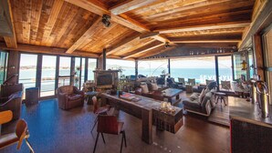 A spacious indoor area with wooden ceilings, a large seating area, and a view of the sea. - Nordsee Manor by Arcadia Collection (Qingdao)