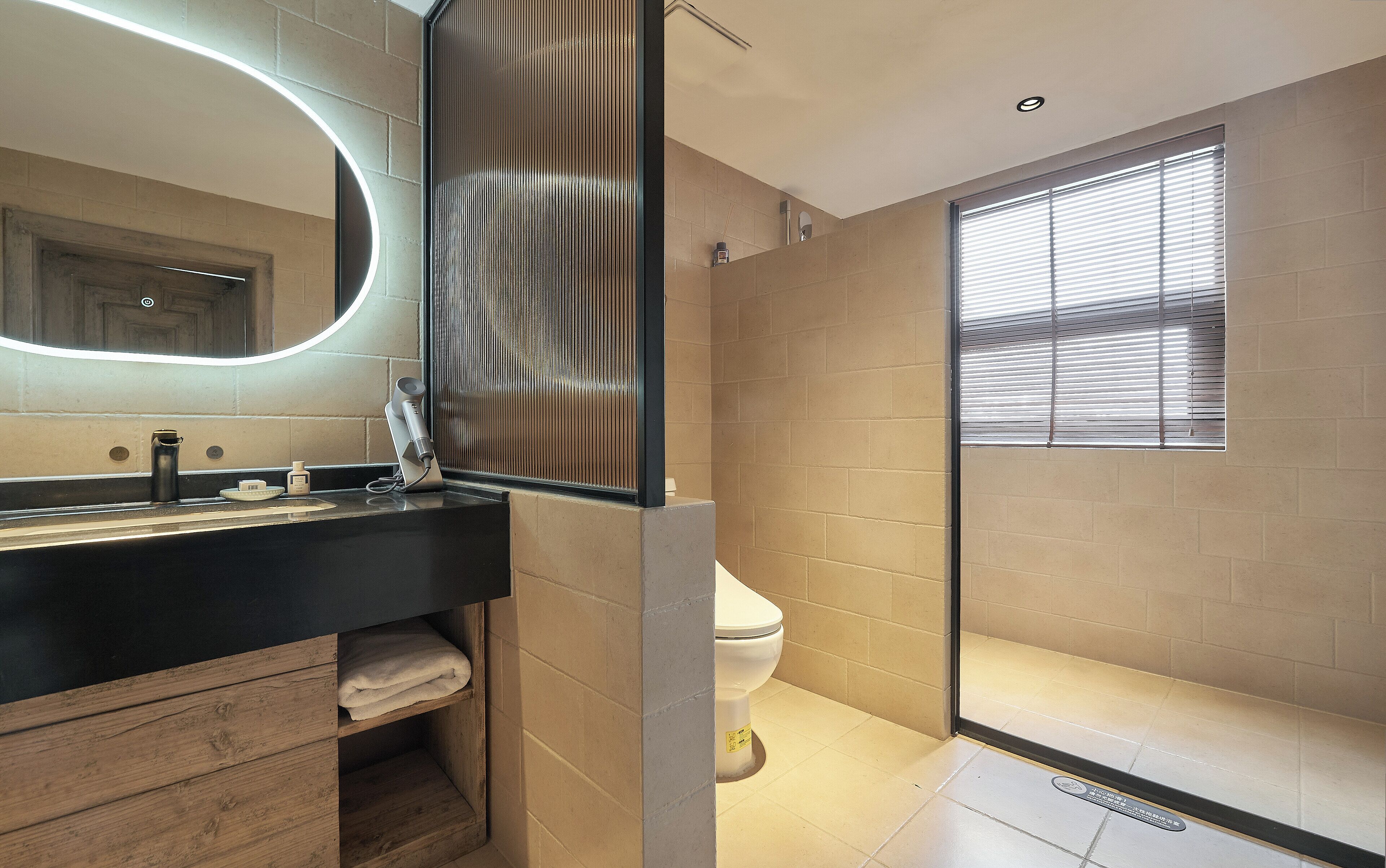 A modern bathroom with a black countertop, a mirror, a toilet, and a shower area.