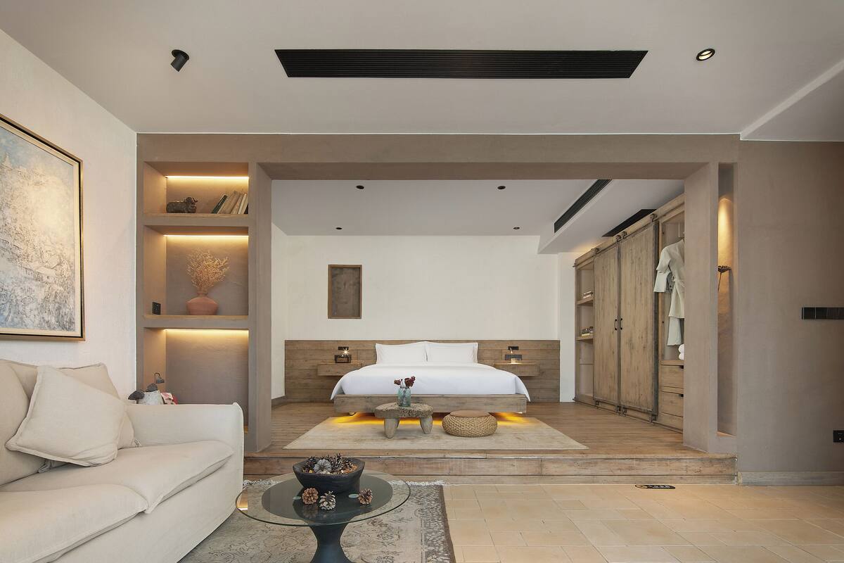 Un dormitorio moderno con una cama grande, mesitas de noche, un armario y una zona de estar con sofá y mesa de centro.