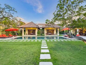 Un resort con piscina central, dos casas de huéspedes y un césped bien cuidado.