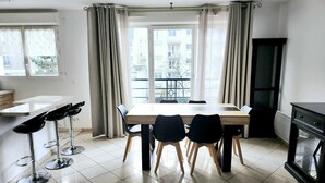 Een moderne keuken met een eethoek, met een grote tafel, barkrukken en uitzicht op buiten.