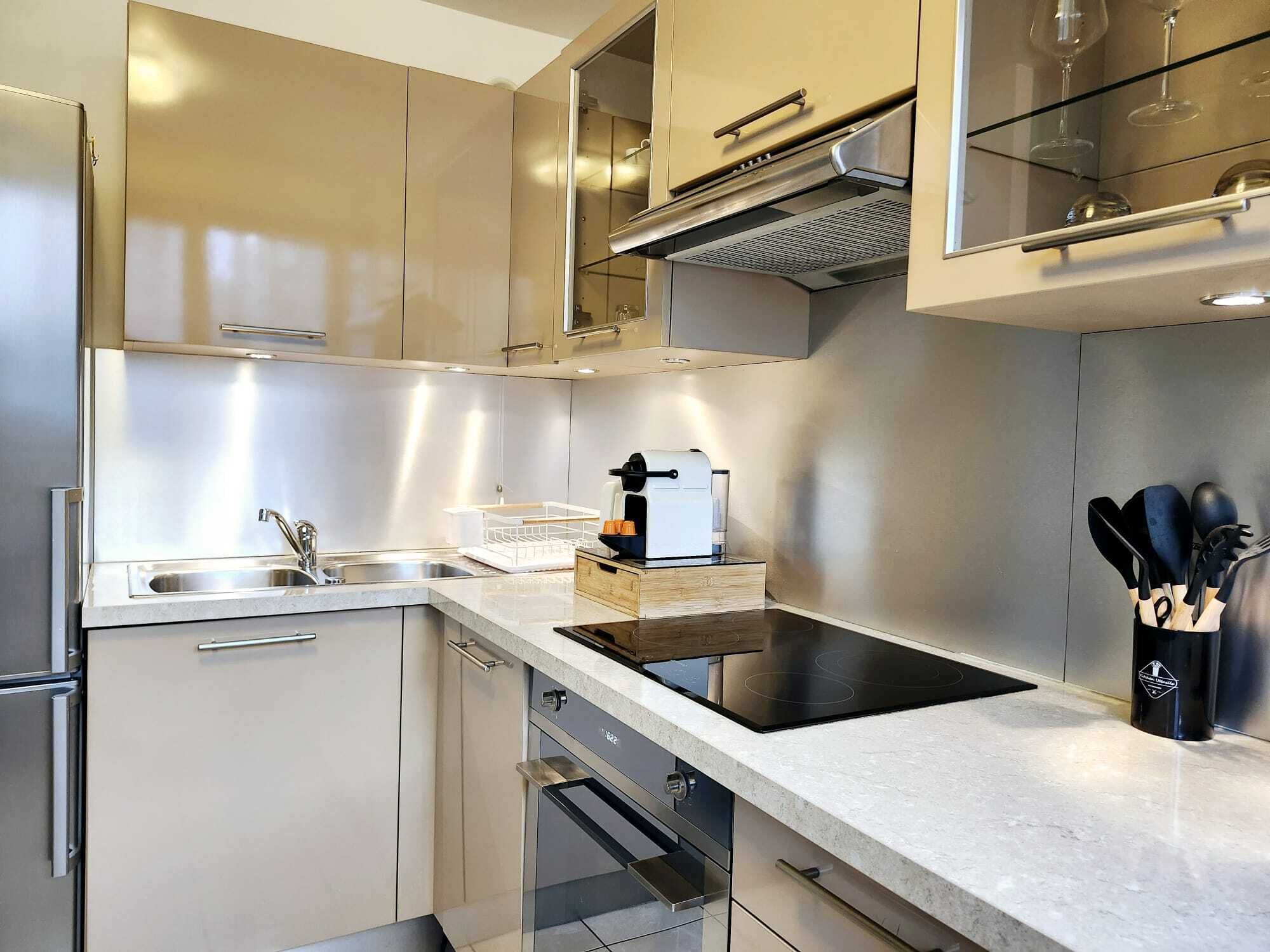 A modern kitchen with stainless steel appliances, a built-in oven, and a coffee machine.