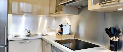 A modern kitchen with stainless steel appliances, a built-in oven, and a coffee machine.