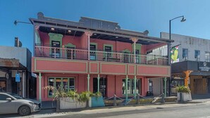 Un immeuble de deux étages avec un balcon, une enseigne indiquant un restaurant et une voiture garée.