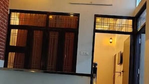A staircase leading to a second floor, a ceiling with hanging lights, and a view of a room with a window and a door. - Nimbal Elegant Home (Jaipur)