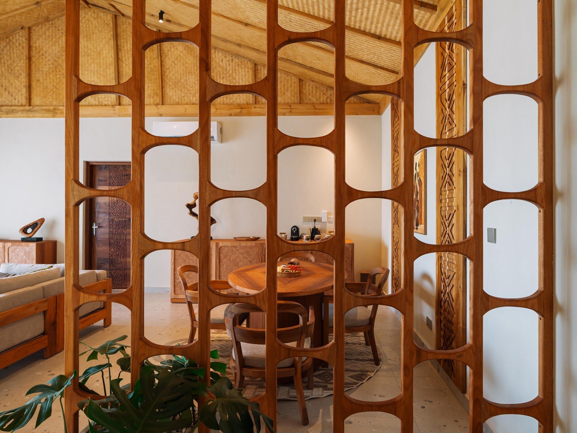 Um quarto com divisória de madeira, uma mesa de jantar com cadeiras, um sofá e uma mesinha de centro.