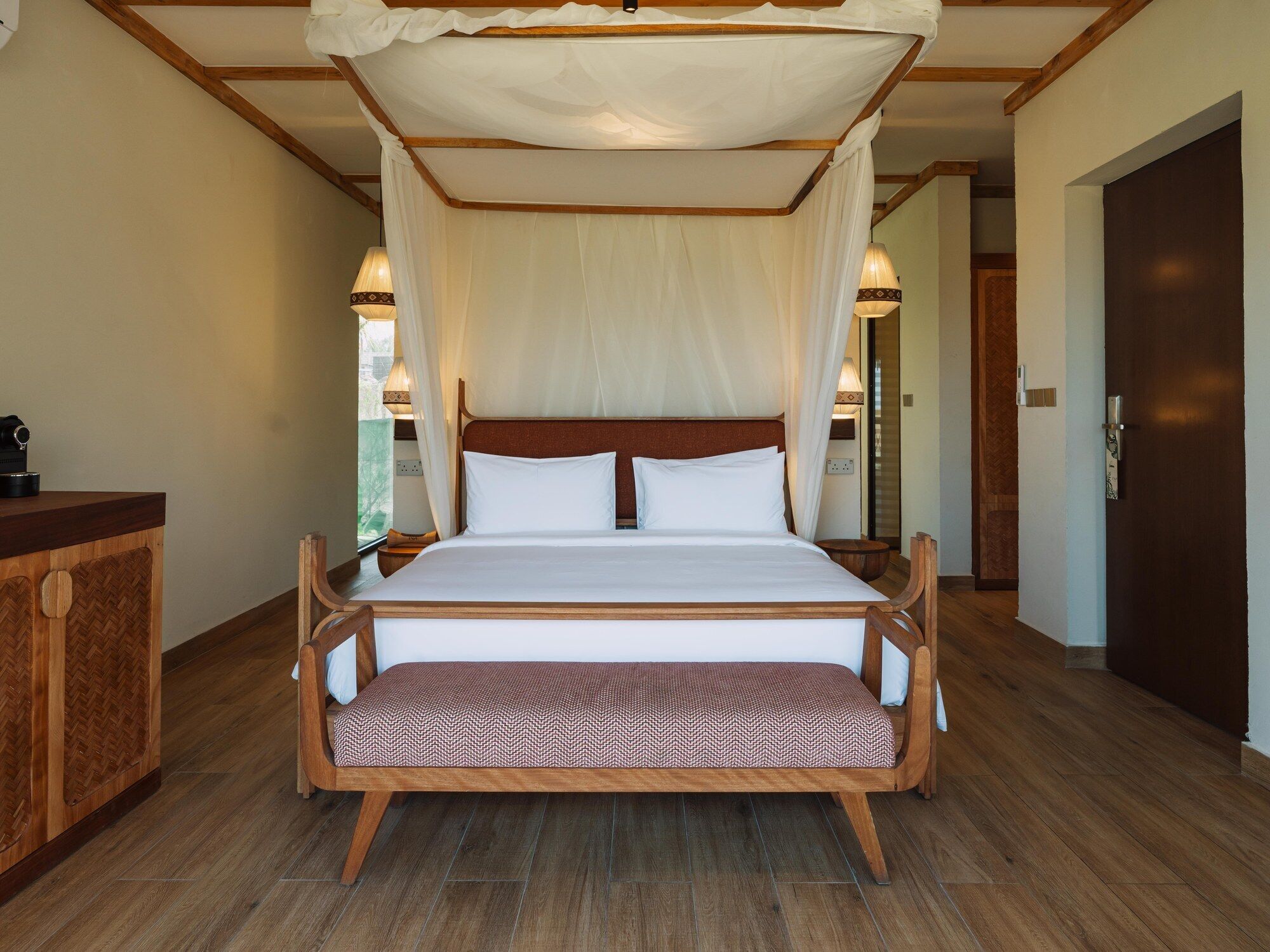 A bed with a canopy, wooden headboard, and bedside tables with lamps.