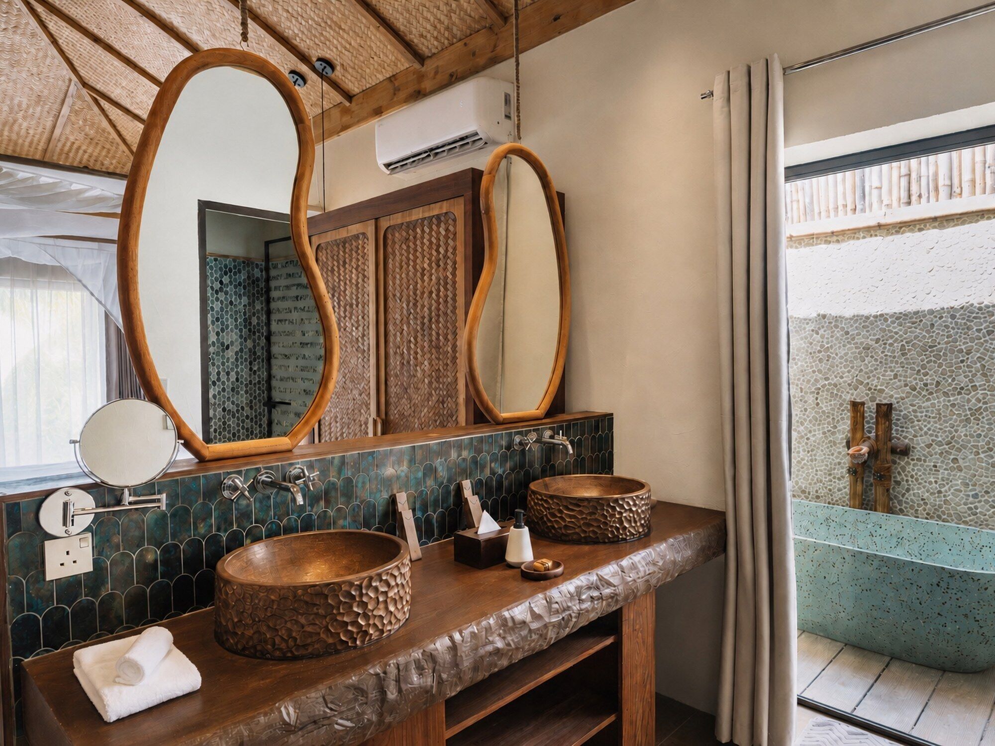 A bathroom with a wooden vanity, two round sinks, a large mirror, and a shower area with a tiled wall.