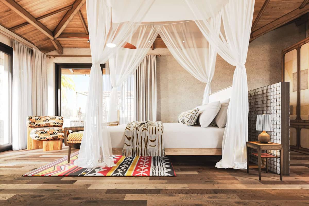 Ein Zimmer mit Baldachinbett, einem gemusterten Teppich und Holzboden.