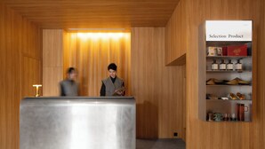 A reception area with a wooden interior, a reception desk, and a shelf displaying products. - Oani (Taipei)