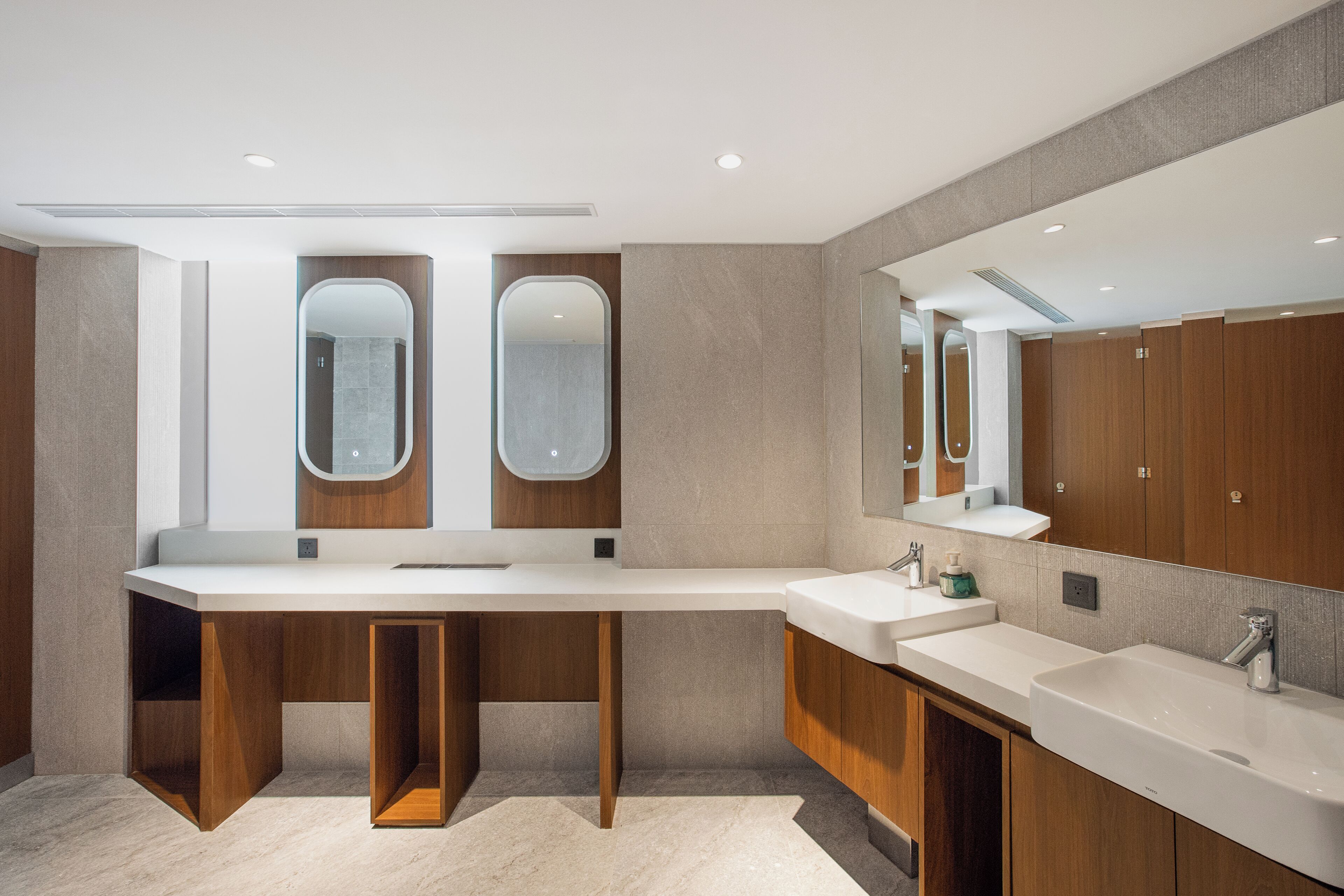 A modern bathroom with a large vanity, two mirrors, and wooden cabinetry.