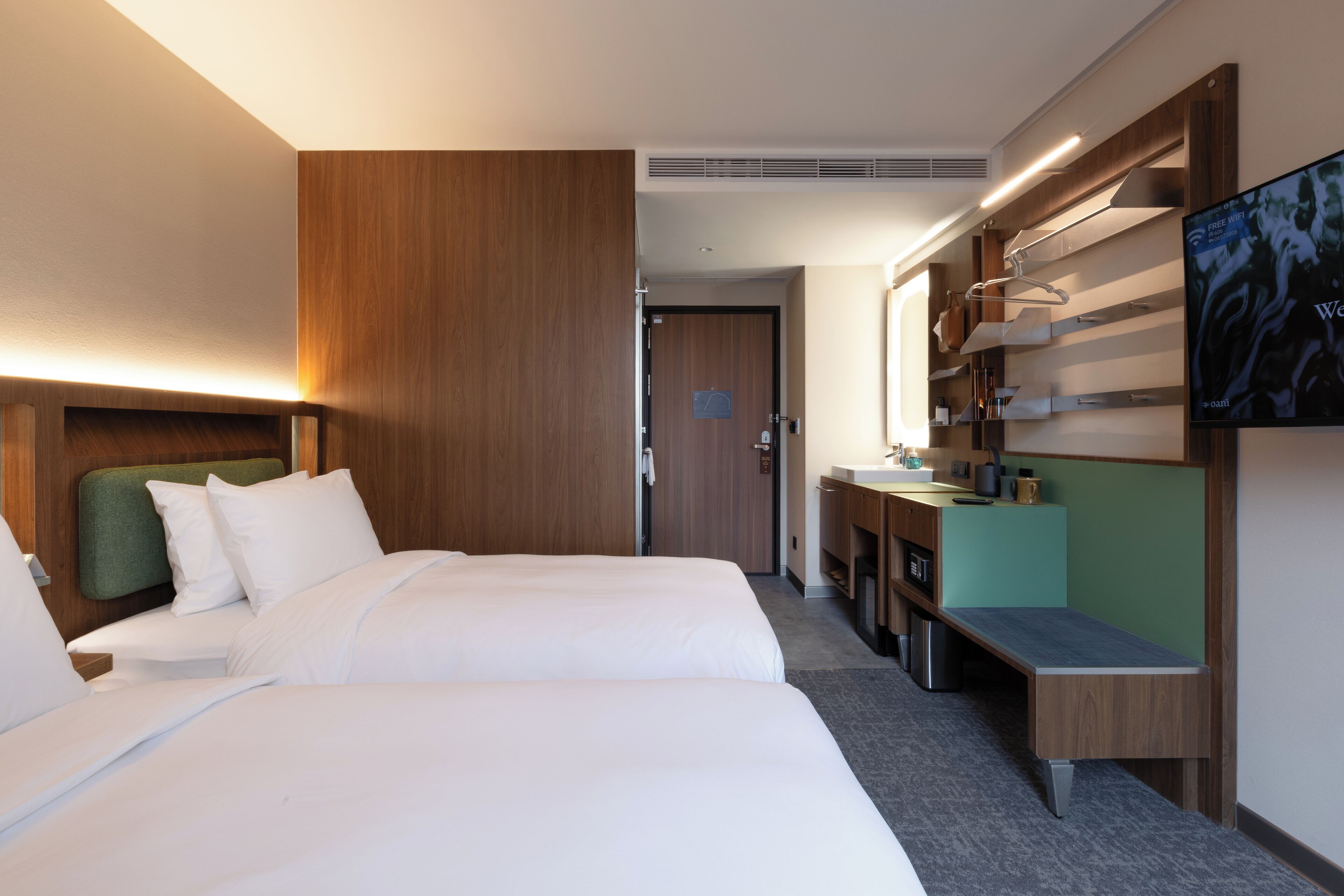 Una habitación de hotel con una cama, un escritorio, un espejo y una televisión.