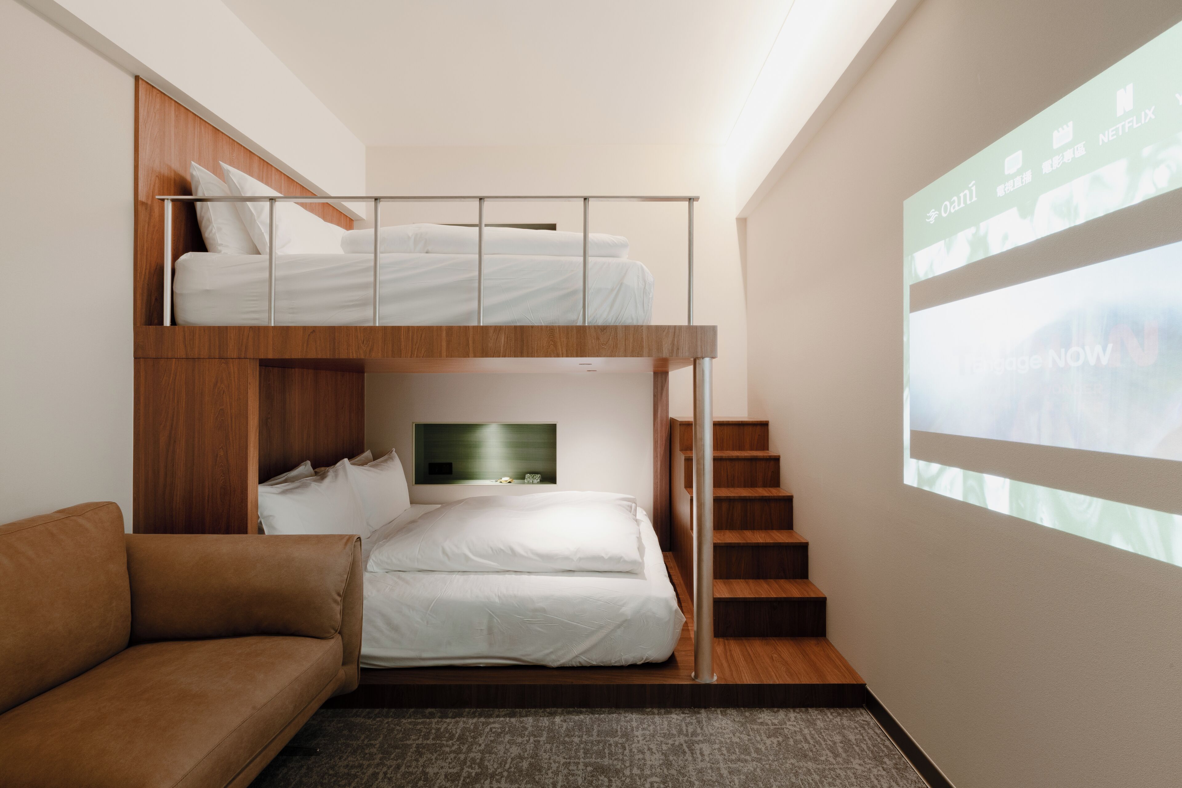 Une chambre d’hôtel moderne équipée d’un lit superposé, d’un canapé, d’une télévision à écran plat et d’un escalier.