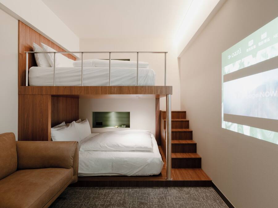 Une chambre d’hôtel moderne équipée d’un lit superposé, d’un canapé, d’une télévision à écran plat et d’un escalier.