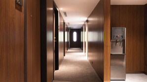 A hotel hallway with wooden walls, a carpeted floor, and a refrigerator on the right. - Oani (Taipei)