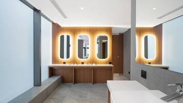 A modern bathroom with a large mirror, three illuminated mirrors above the sink, and a single sink with a chrome faucet.
