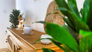 Un cofre de madera con objetos decorativos encima, incluyendo un jarrón blanco y una cesta tejida.