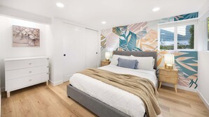 Un dormitorio con cama, cómoda, mesita de noche y ventana con vistas.