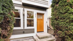 Ett modernt hus i två våningar med en träfasad, en brevlåda och en liten veranda.