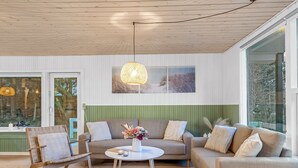 A modern living room with a wooden ceiling, a green accent wall, and a large window. - "Felicia" -  from the sea by Interhome (Hals)