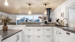 A modern kitchen with white cabinets, a wooden ceiling, and pendant lighting. - "Felicia" -  from the sea by Interhome (Hals)