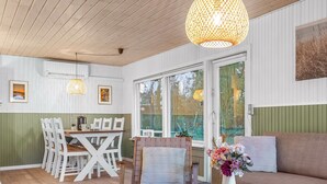 A cozy living room with a wooden ceiling, a dining area with a table and chairs, and a large window providing a view of the outdoors. - "Felicia" -  from the sea by Interhome (Hals)