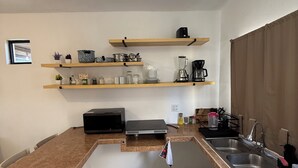 Una cocina con una encimera larga, microondas, cafetera y fregadero.