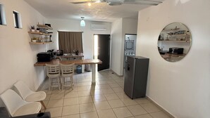 Un espacio habitable compacto con comedor, kitchenette y una zona de estar con sofá y sillones.