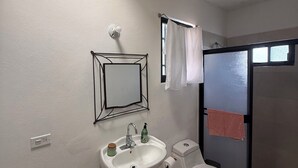 Un baño con lavamanos pedestal, inodoro y zona de ducha.