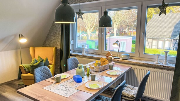 A dining area with a wooden table, chairs, and hanging pendant lights. - Die Dorfperle by Interhome (Wanna)