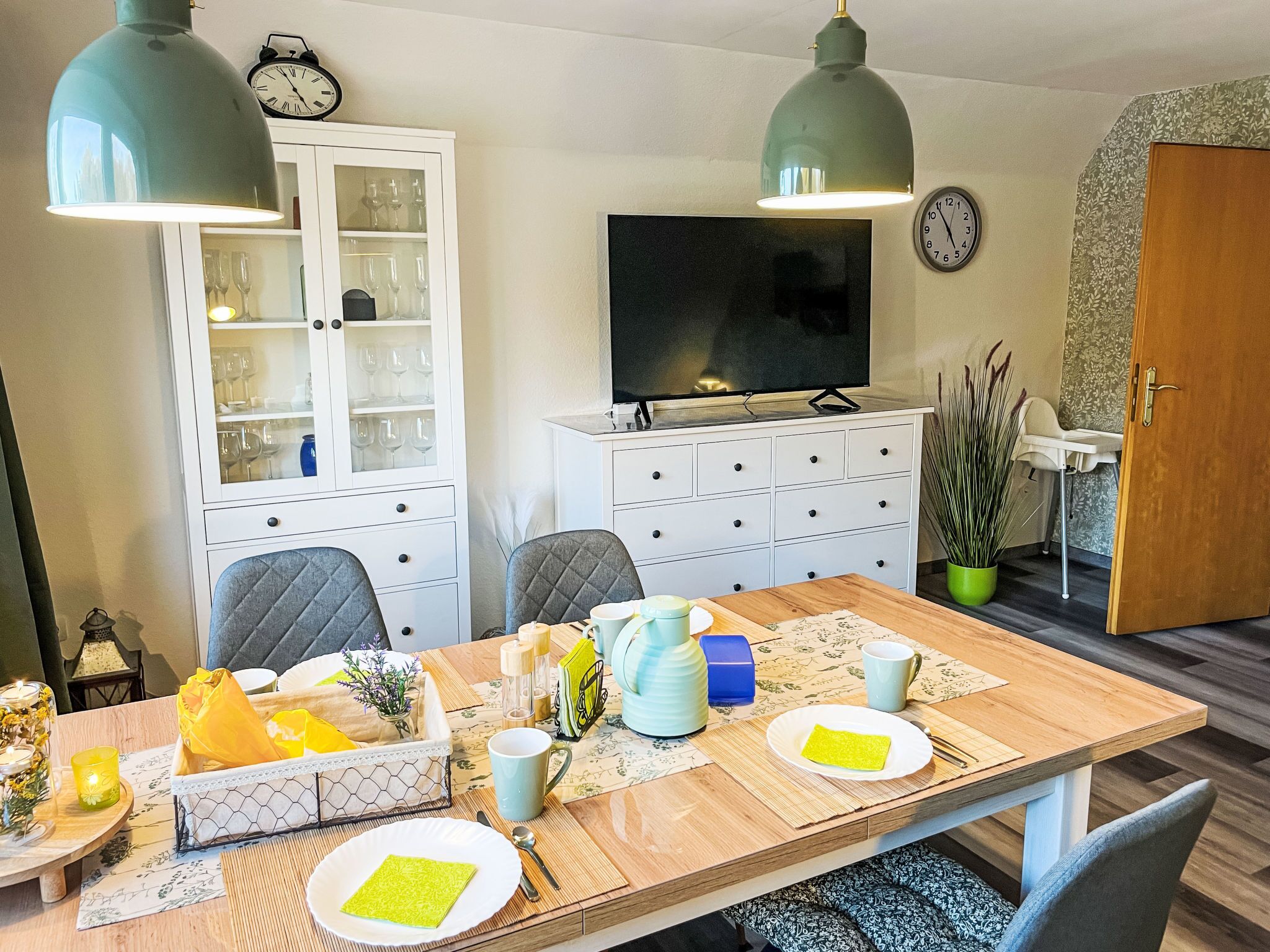 Un coin repas comprenant une table en bois, des chaises et un buffet aux portes vitrées.