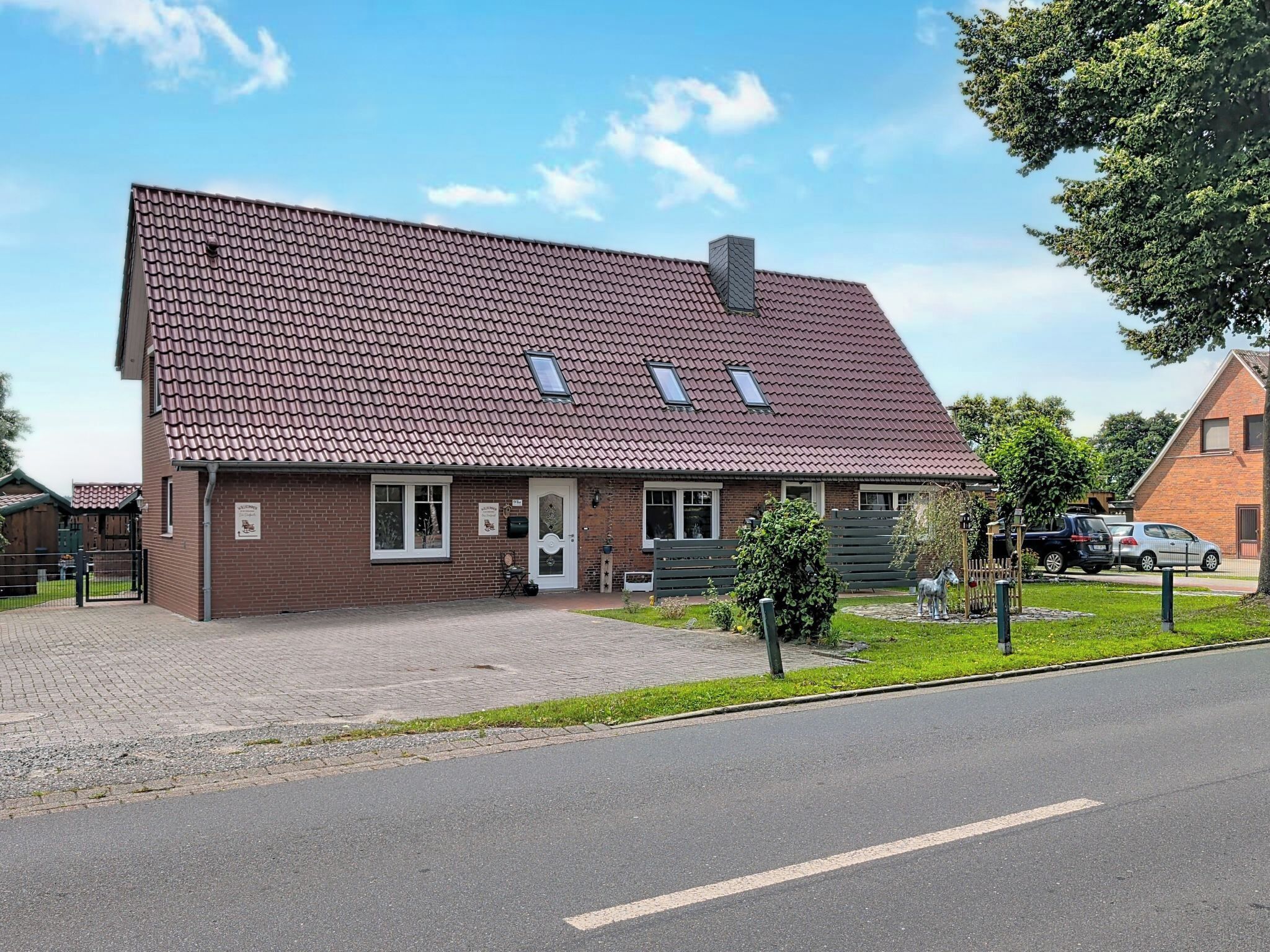 A two-story house with a sloped roof, a front porch, and a small garden area.