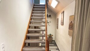 A staircase with wooden steps and a handrail, leading to a landing with a small table and chairs. - Die Dorfperle by Interhome (Wanna)