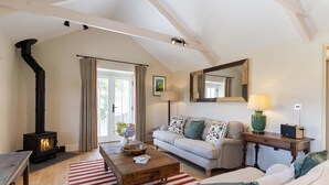 Una sala de estar acogedora con chimenea, un sofá, una mesa de centro y un espejo grande.