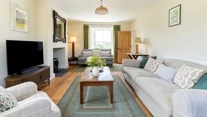Ein Wohnzimmer mit Fernseher, Sofa, Couchtisch und Kamin.