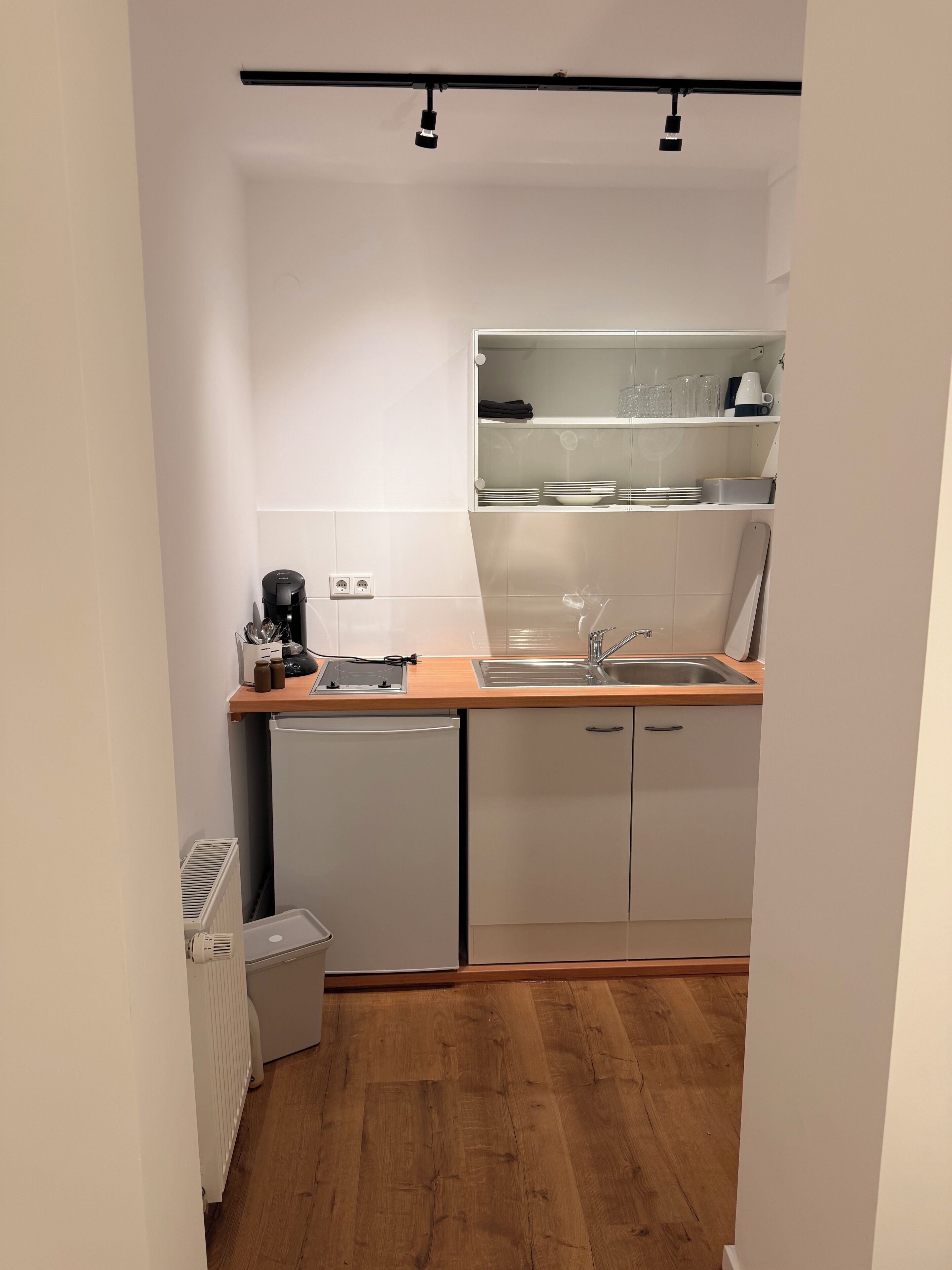 A compact kitchen with a dishwasher, a sink, and a countertop with a coffee maker.