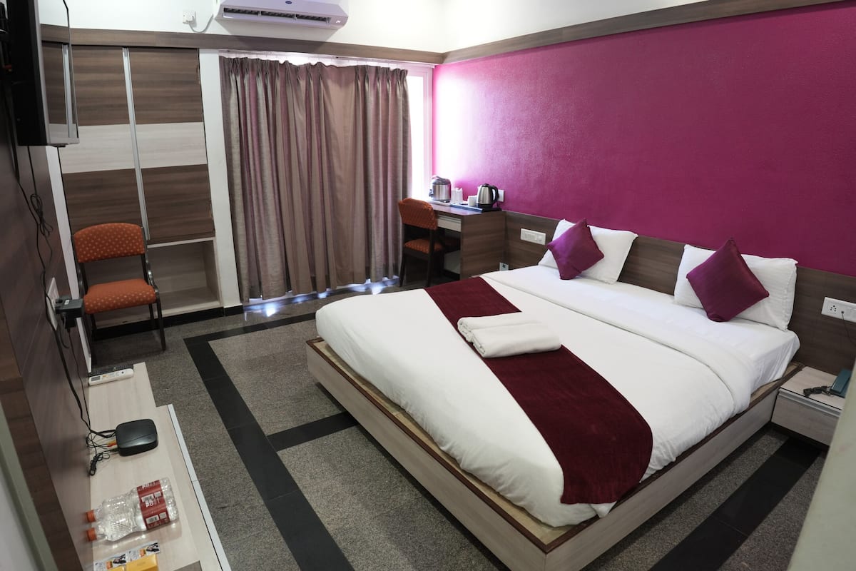A hotel room with a bed, desk, chair, and a TV.