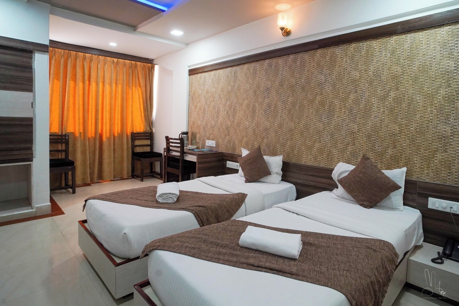 A hotel room with two beds, a desk, and a chair.