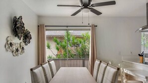 Un comedor con mesa y sillas, un ventilador de techo y vistas al exterior.