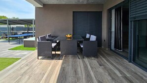 An outdoor patio with a table and chairs, a small garden area, and a covered seating area.