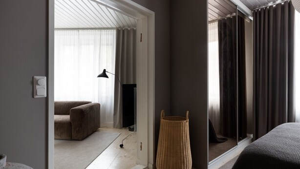 Une chambre d’hôtel moderne, dotée d’un grand miroir, d’un canapé, d’une télévision et d’un panier en osier.