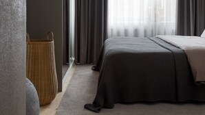 Une chambre à coucher moderne avec un grand lit, des rideaux foncés, un luminaire suspendu et un panier en osier.