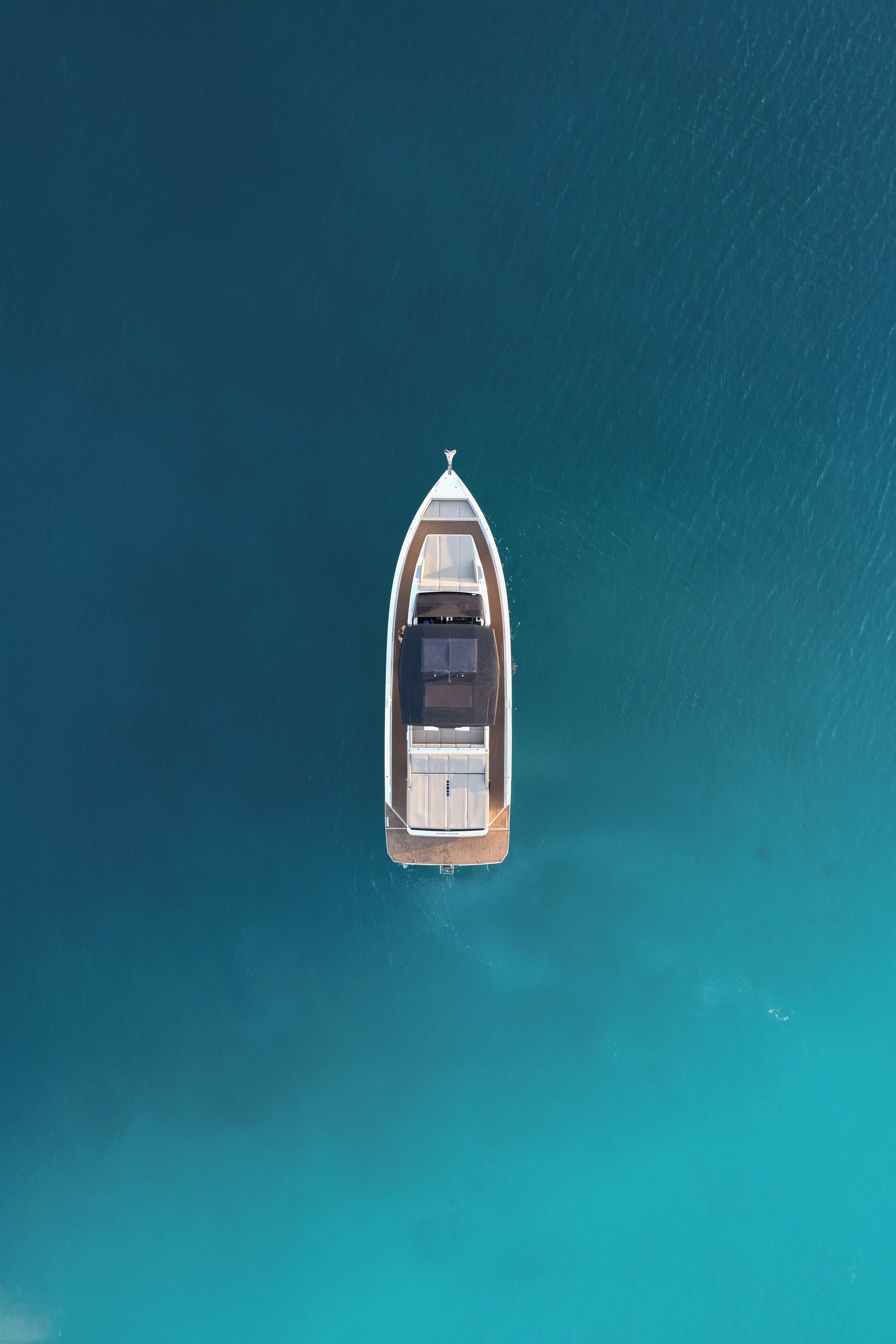 An aerial view of a small, single-deck boat with a covered seating area and a small cabin at the rear.