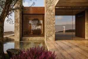 A modern architectural structure with stone walls, a wooden deck, and a clear view of the surrounding landscape. - Kenshō Paros (Paros)