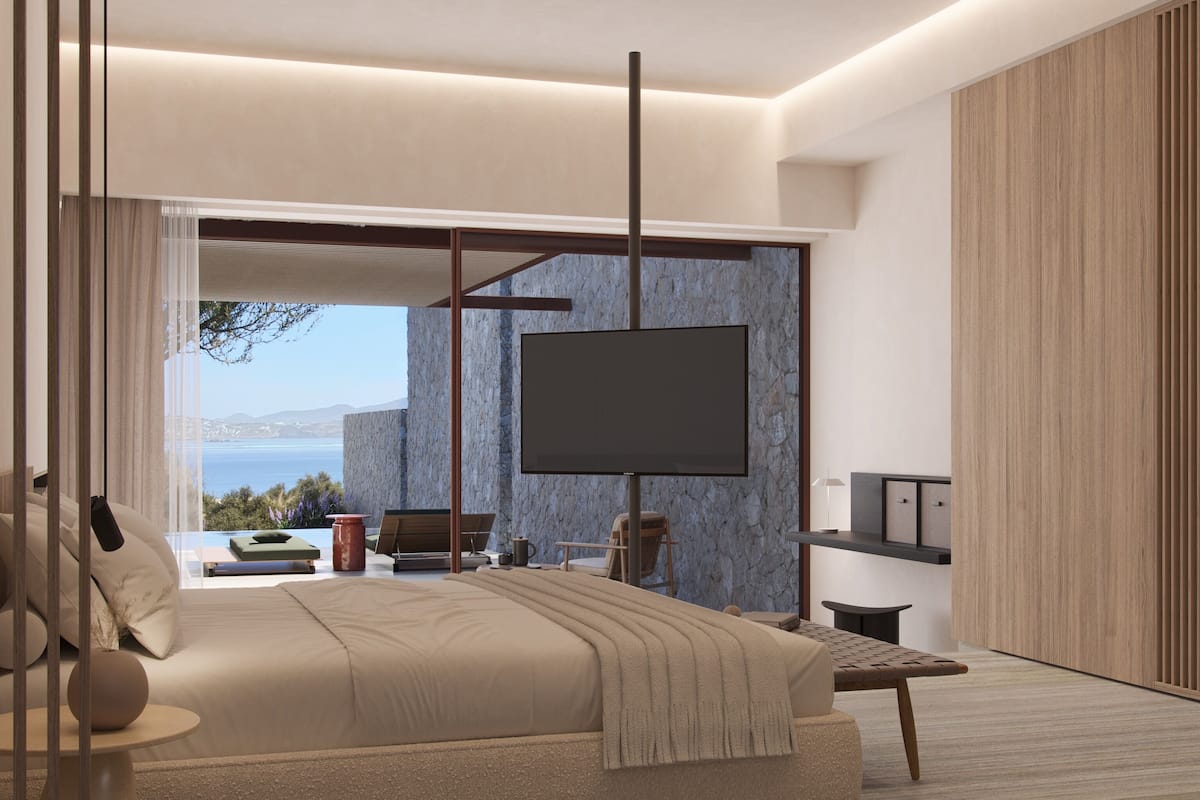 A modern bedroom with a large bed, a TV mounted on the wall, and a view of the sea.