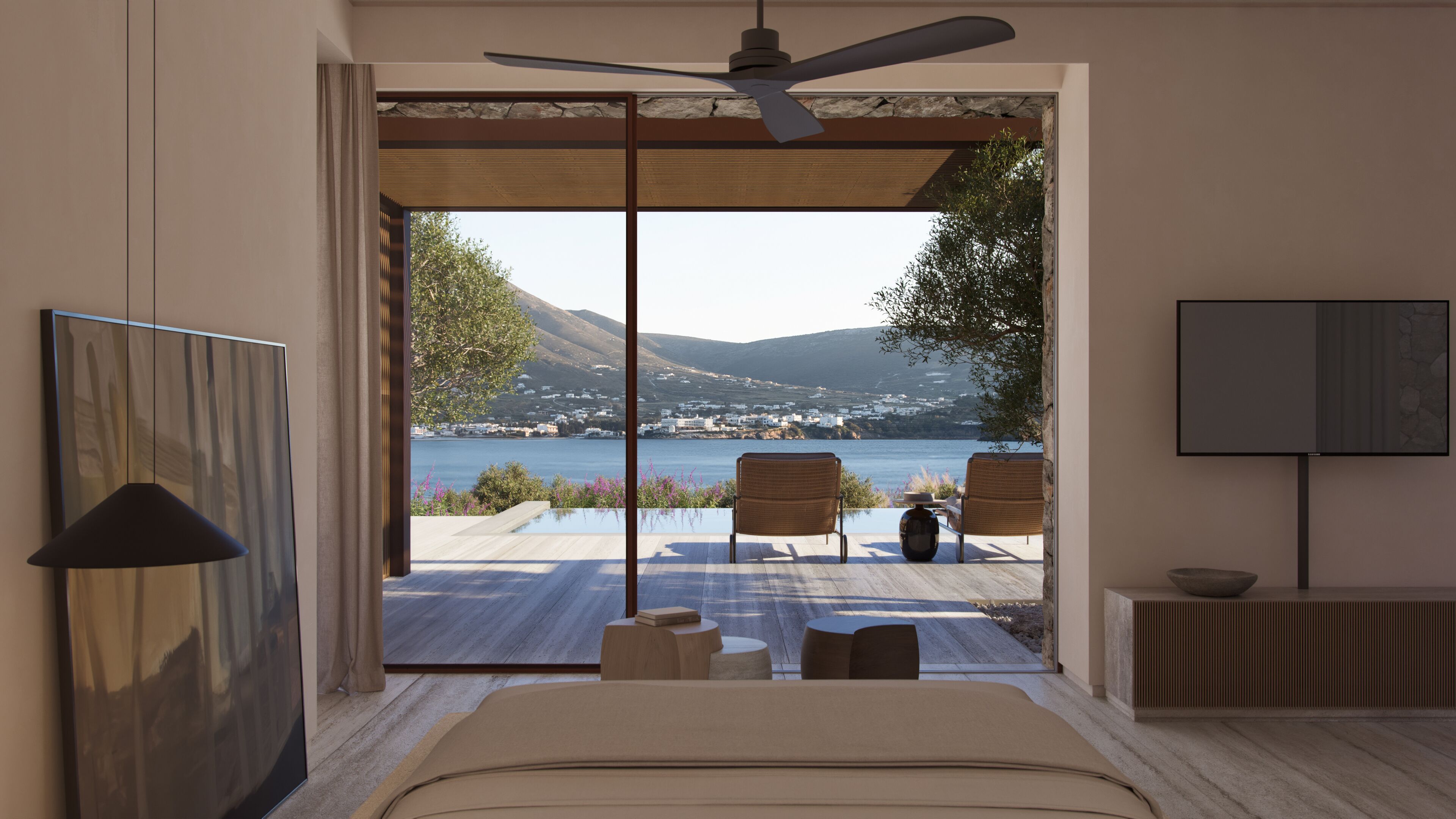 A bedroom with a large window, a ceiling fan, a TV, and a view of a lake and mountains.
