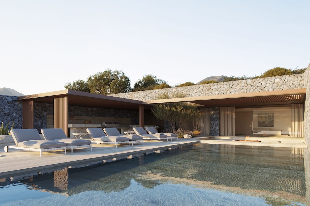 A modern outdoor pool area with lounge chairs and a stone wall backdrop.
