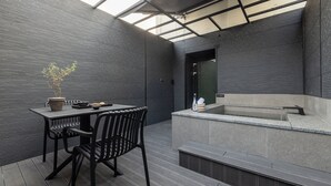A modern outdoor seating area with a table and chairs, a potted plant, and a hot tub. - Mitasuya Ryokan Hotel by Anook Pyeongtaek Station (Pyeongtaek)